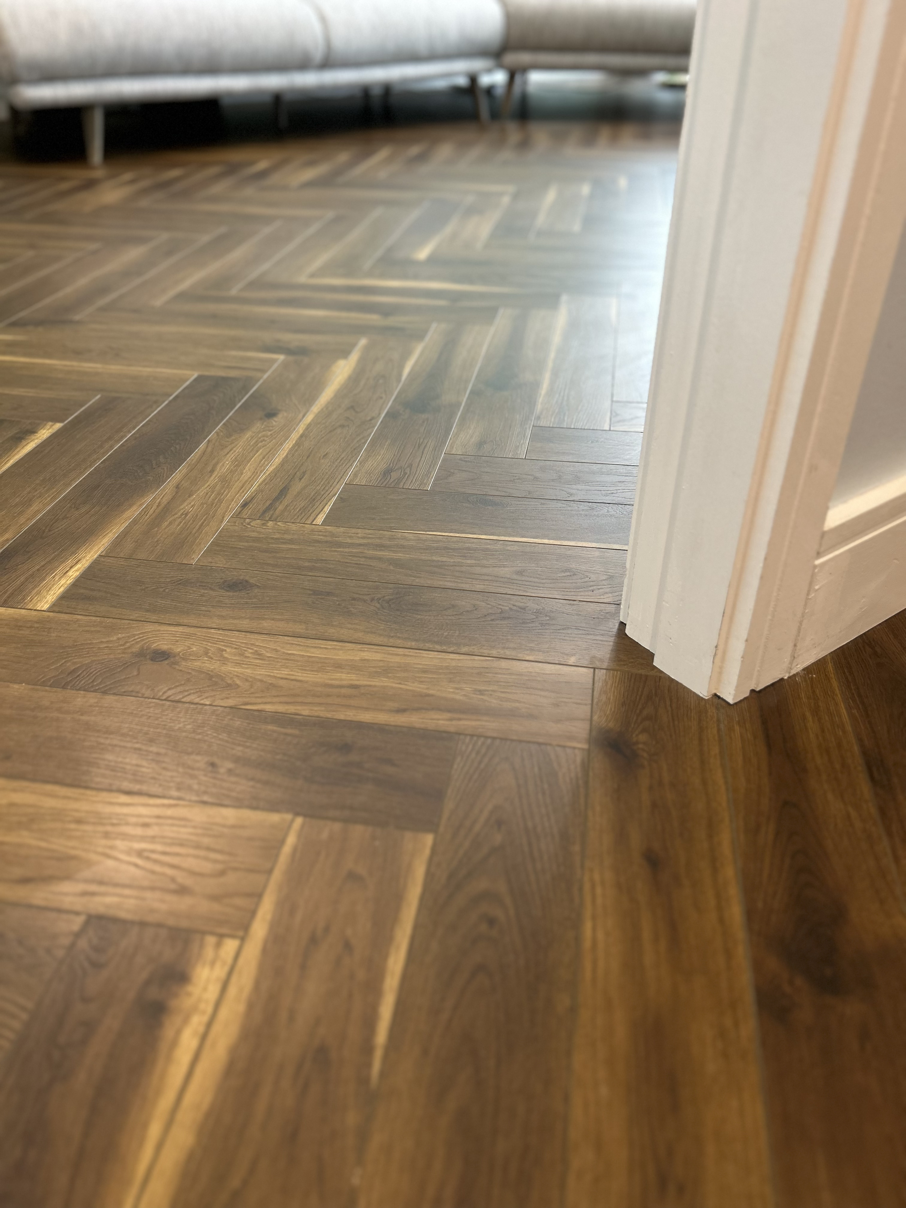 Close up of herringbone flooring around a white doorway.