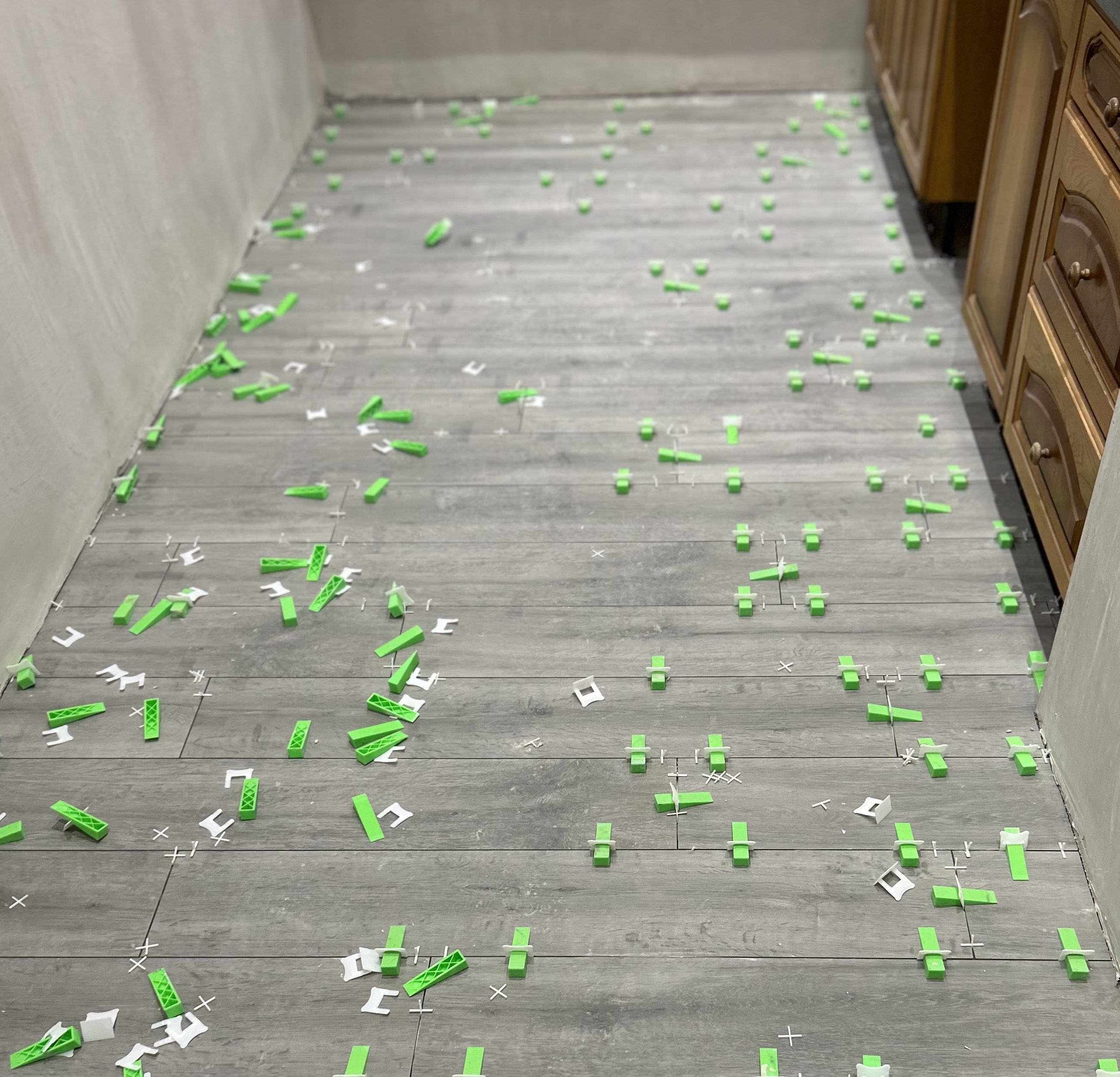 Tiling in a hallway with greens clips between each tile